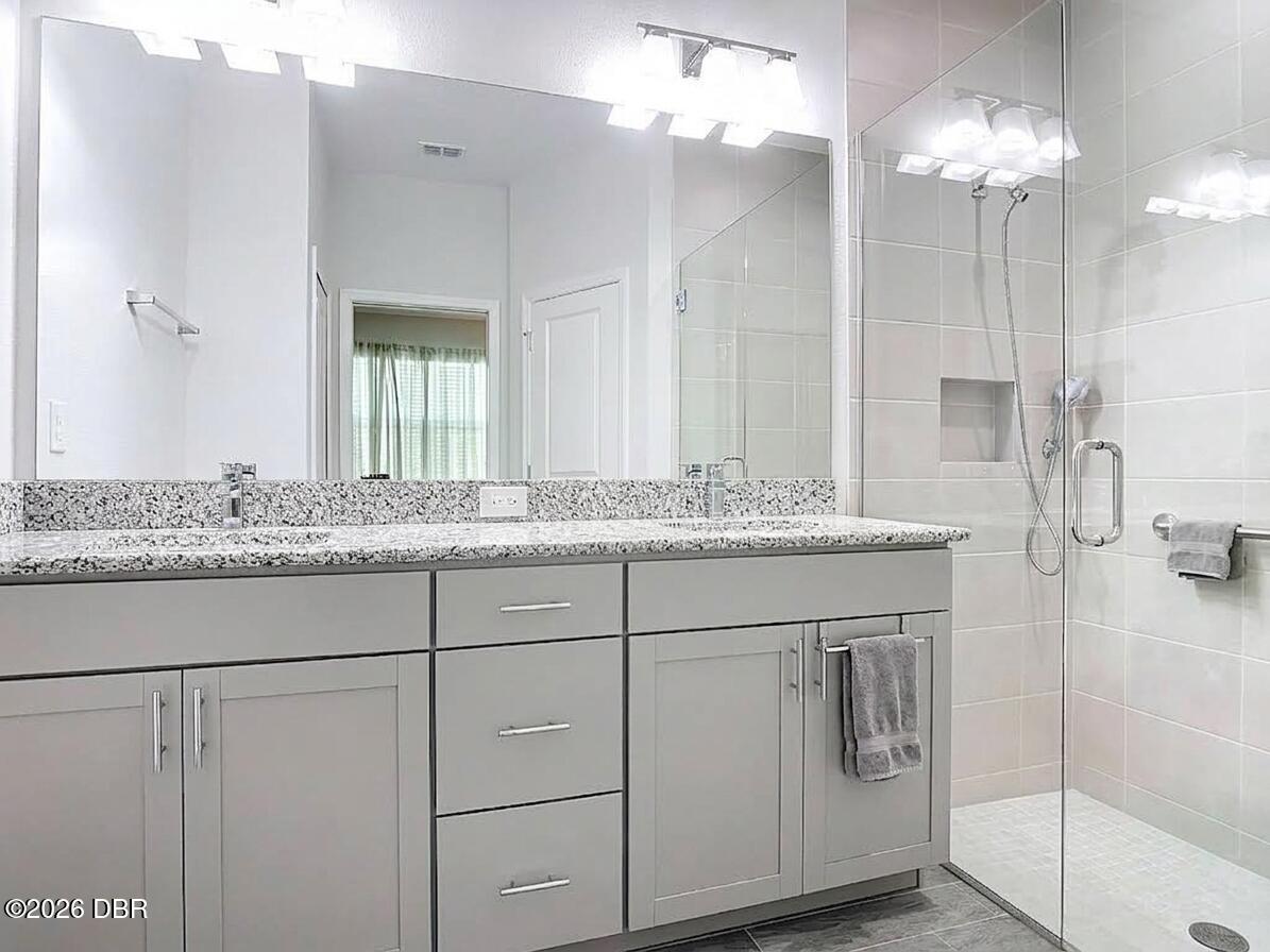 Modern bathroom with a long gray vanity and glass-enclosed tiled shower.
