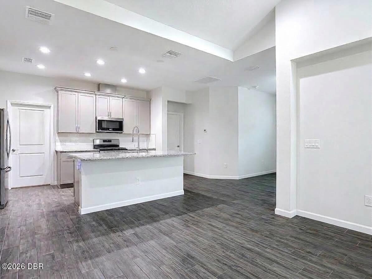 Open kitchen with white cabinets, stainless steel appliances, and a granite-topped peninsula.