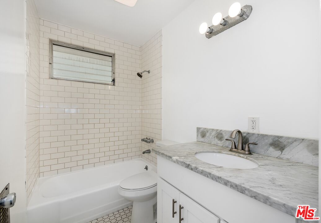 Bathroom with a subway-tile tub surround and gray marble vanity.