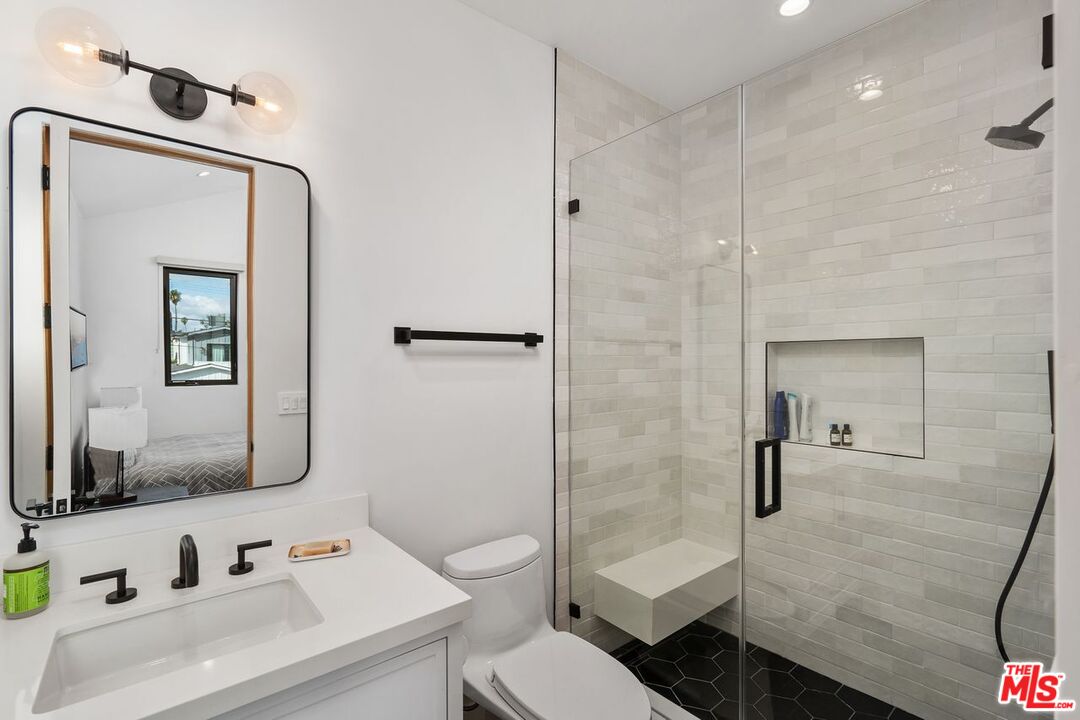 Modern bathroom with a glass-enclosed shower, built-in bench, and dark hexagonal floor tile.