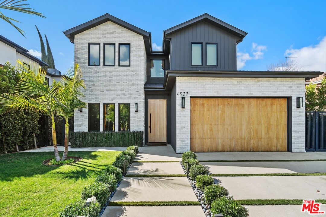 Two-story home at 4937 Rubio Ave with white brick, dark siding, and a wood garage door.