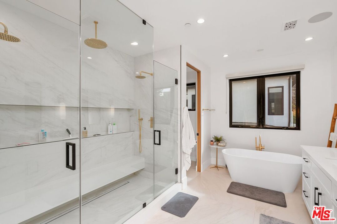 Bathroom with a marble walk-in shower, built-in bench, and freestanding tub.