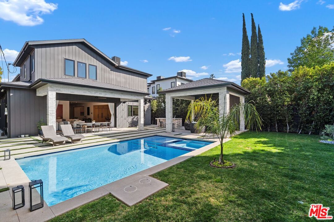 Rear of a two-story home with a swimming pool, covered patio, and landscaped lawn.