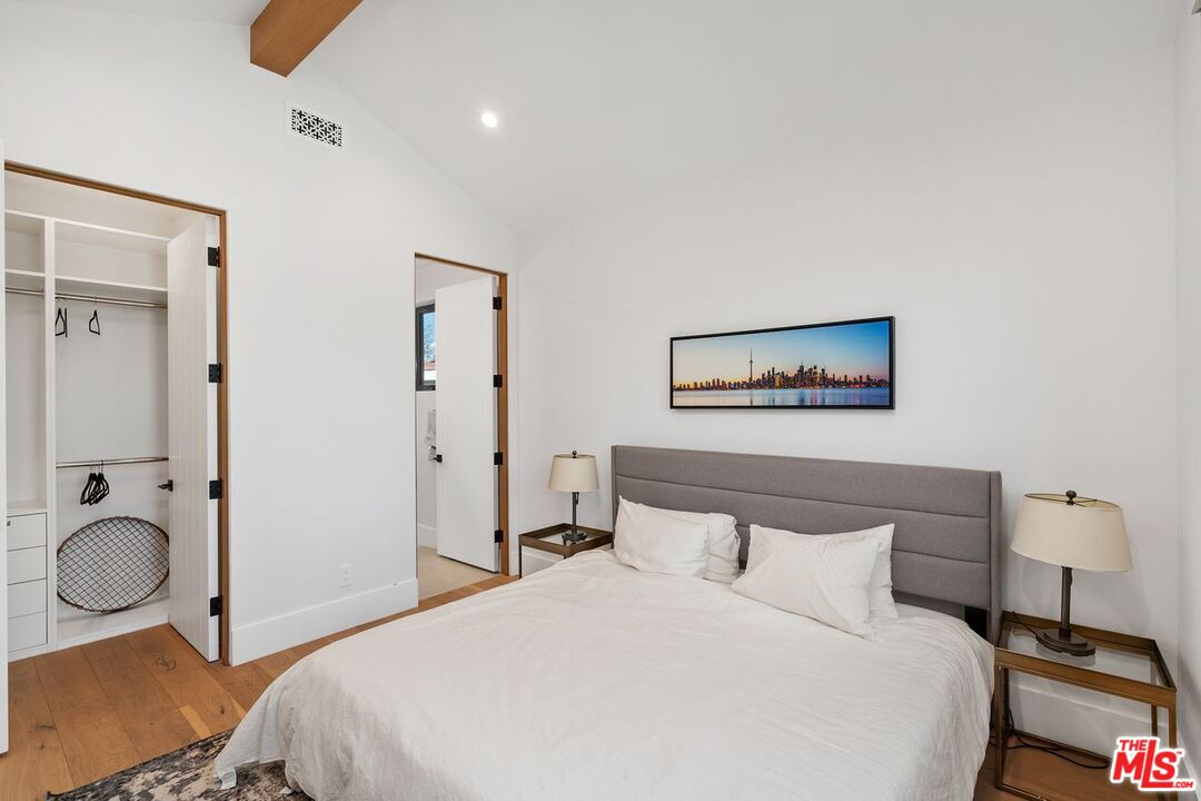 Bedroom with a large bed, gray headboard, open closet, and framed city skyline print.
