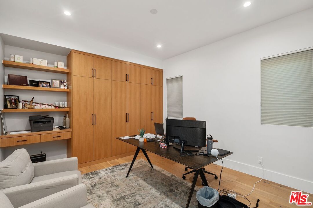 Home office with built-in wood cabinetry, open shelves, and a desk with computer monitors.