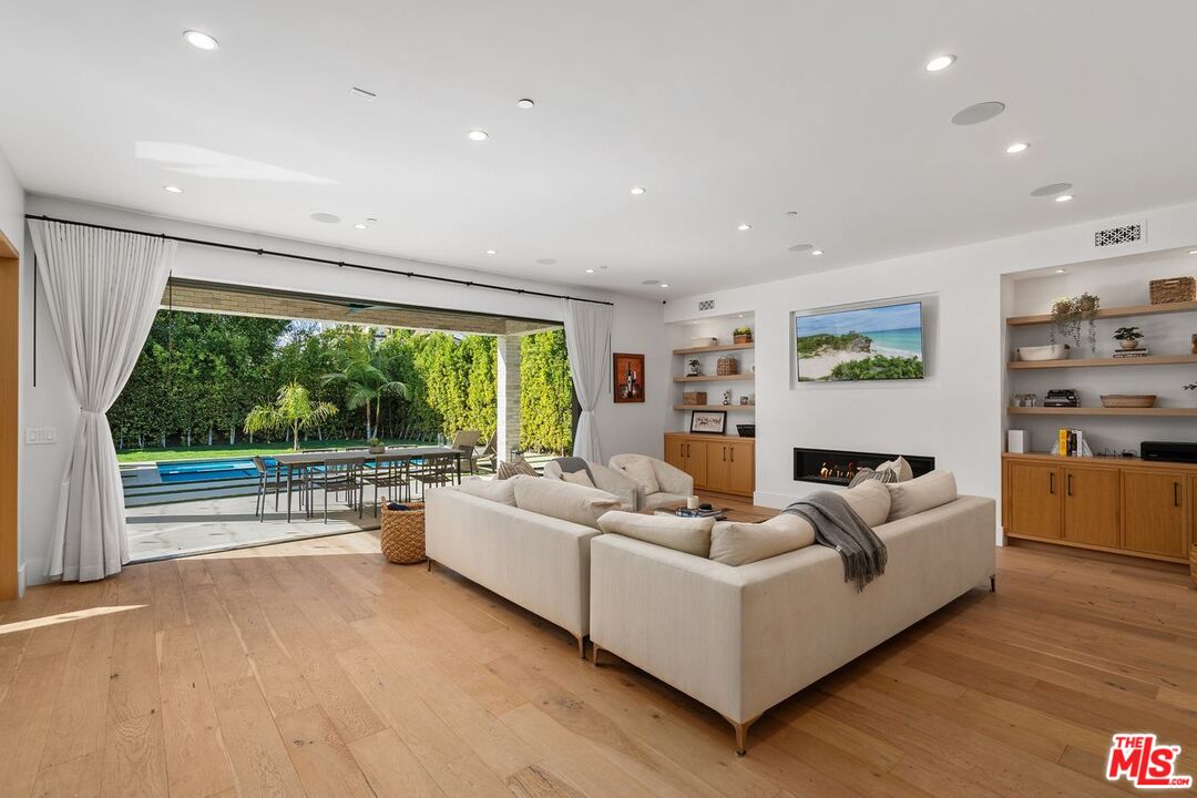 Living room with a white sectional and wide doors opening to a patio and swimming pool.