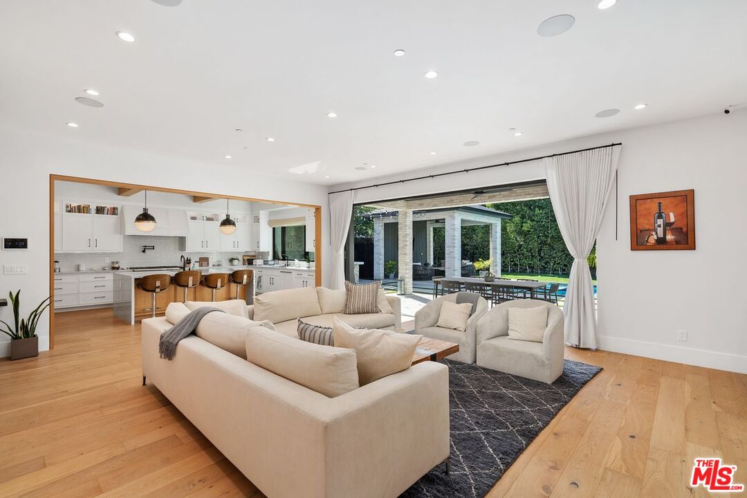 Open-plan living room and kitchen with cream seating and wide doors opening to a covered patio.