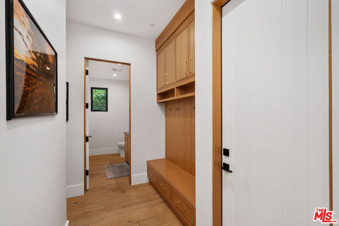 Hallway with built-in wood bench and cabinetry beside an open bathroom doorway.