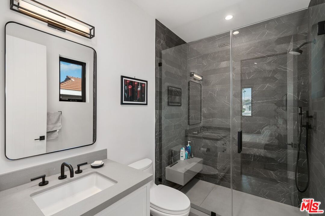 Modern bathroom with a white vanity and dark gray tiled glass shower.