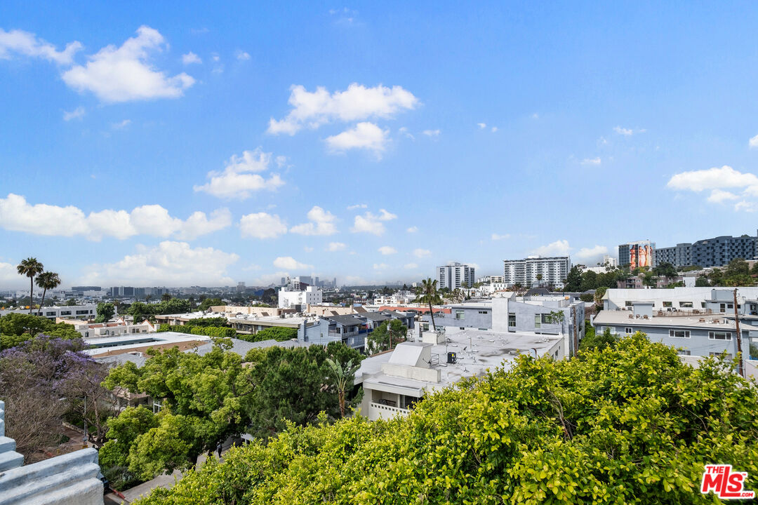 West Hollywood city view with leafy rooftops, mid-rise buildings, and a distant skyline.