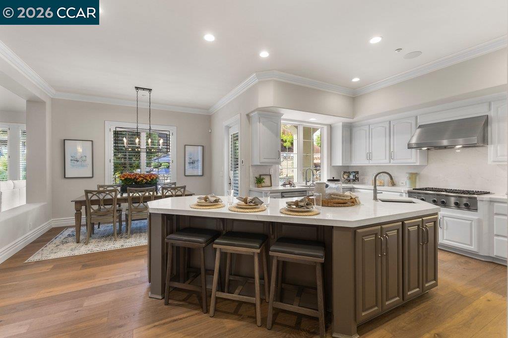 Kitchen with a large dark island, three bar stools, and an adjoining dining area.