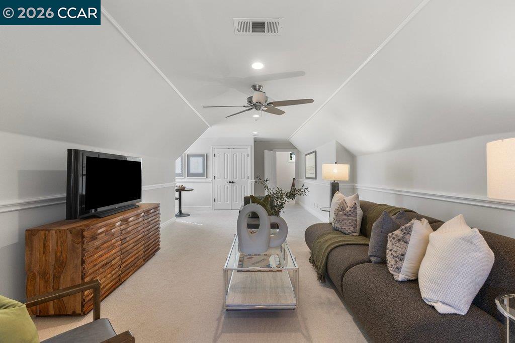 Upstairs sitting room with a sectional sofa, television, and ceiling fan.