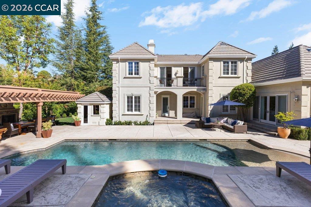 Rear view of a two-story home overlooking a swimming pool and raised spa.