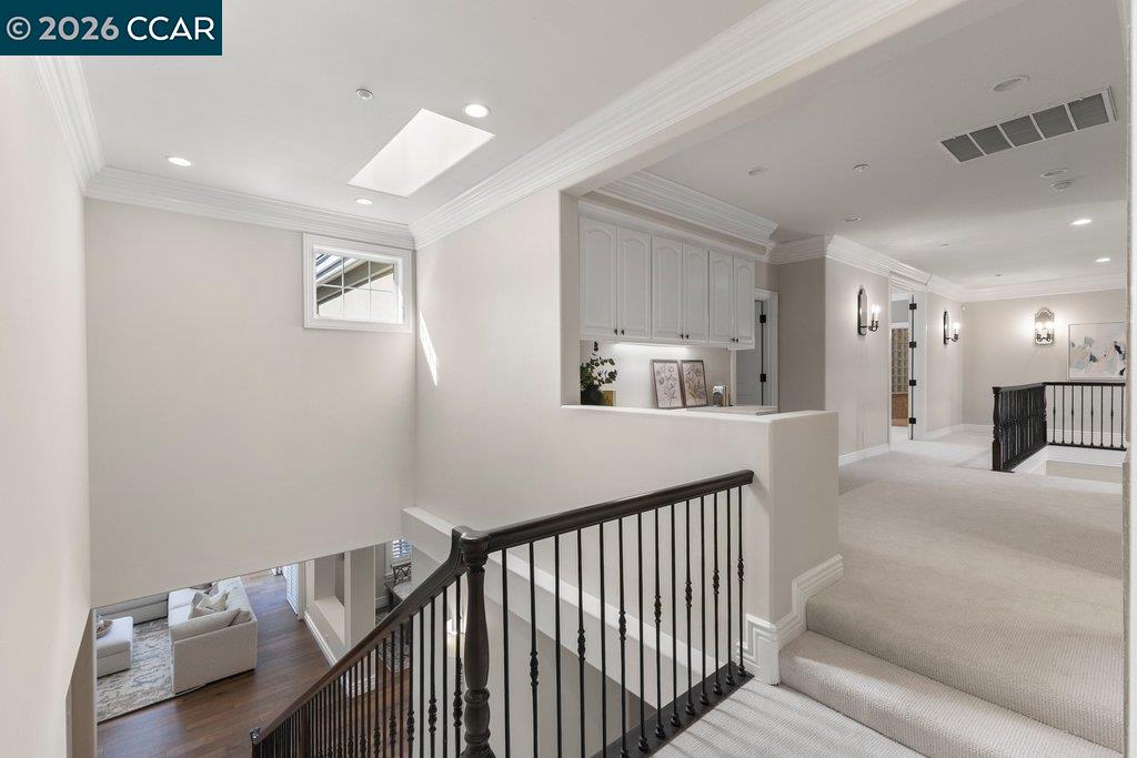 Upstairs landing with dark stair railings, carpeted floors, and built-in cabinets.