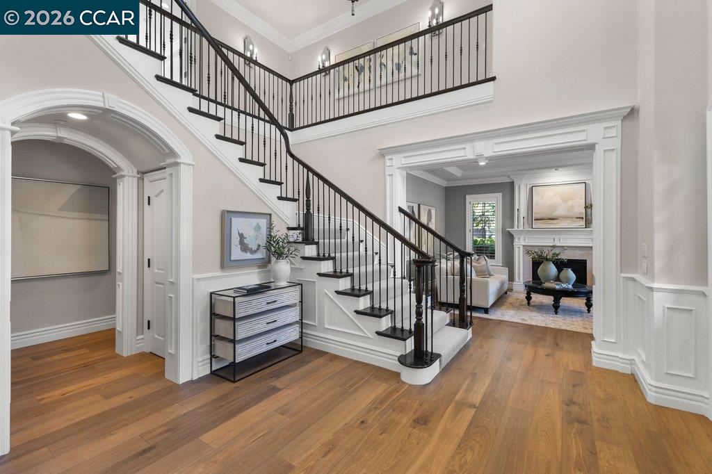Two-story foyer with a sweeping staircase, black iron railings, and hardwood floors.