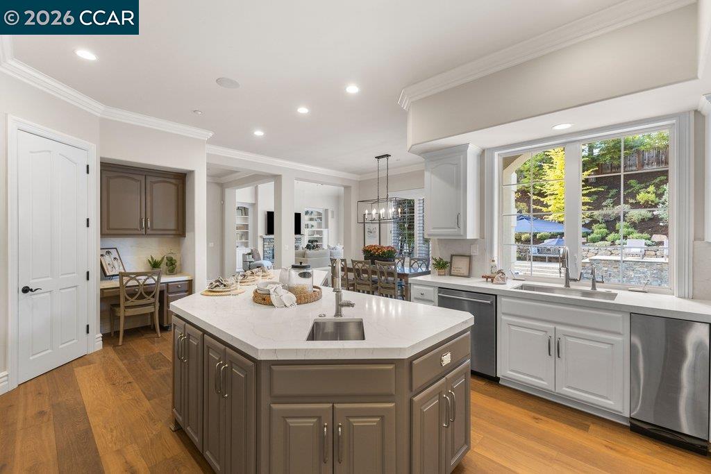 Kitchen with a large brown island, white countertops, and a sink overlooking the landscaped backyard.