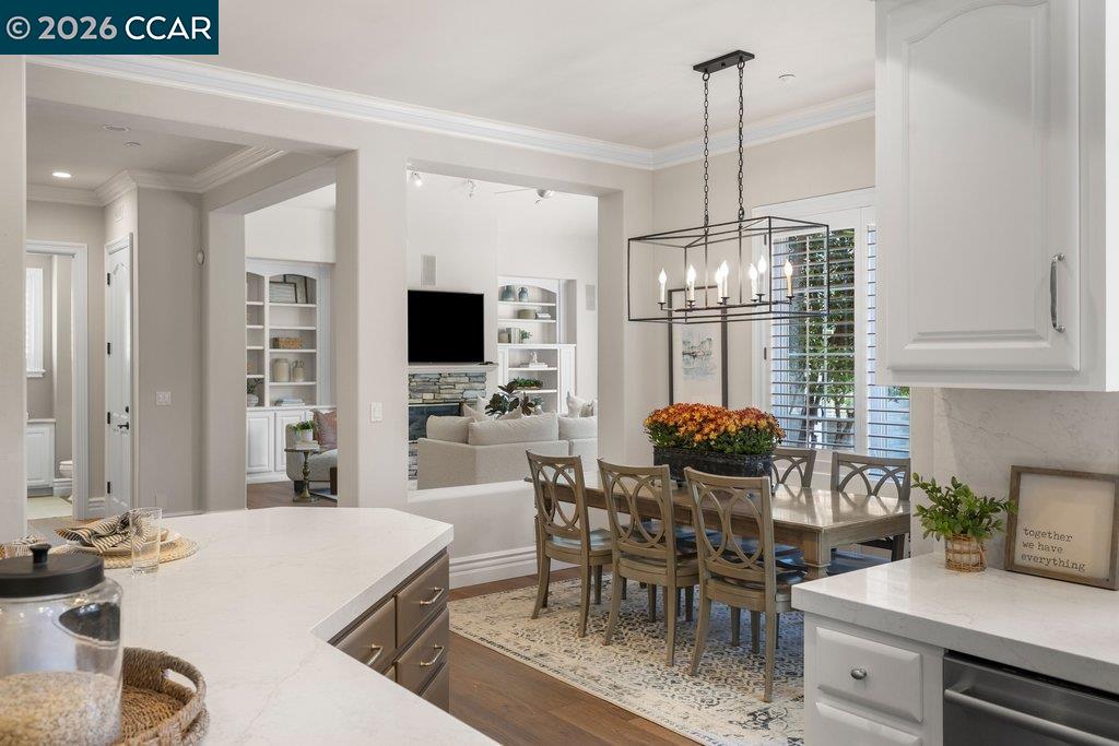 Open kitchen and dining area with white stone counters, a wood table, and a lit chandelier.