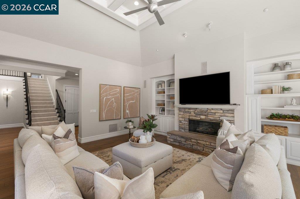 Living room with a stone fireplace, built-in shelving, and a vaulted ceiling with a skylight.