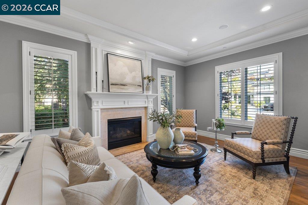 Staged living room with a white fireplace, plantation shutters, and patterned armchairs.