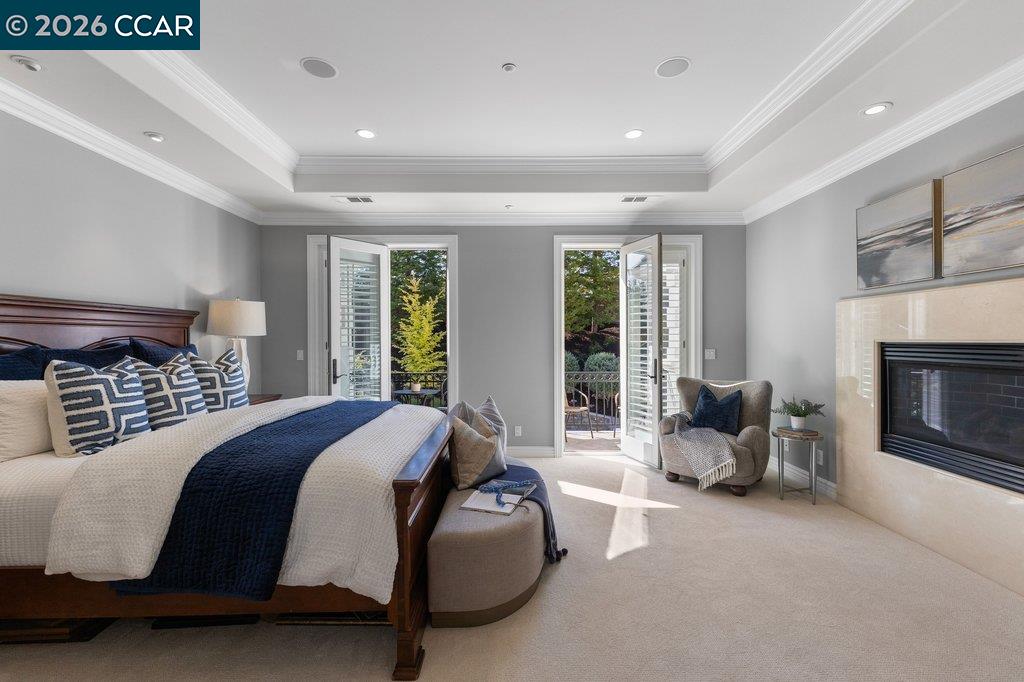 Bedroom with a large bed, fireplace, and open doors to a garden.