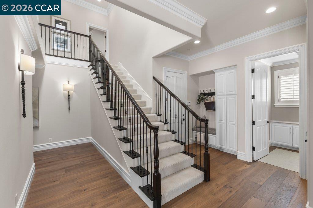 Two-story foyer with a carpeted staircase, dark iron railing, and hardwood floors.
