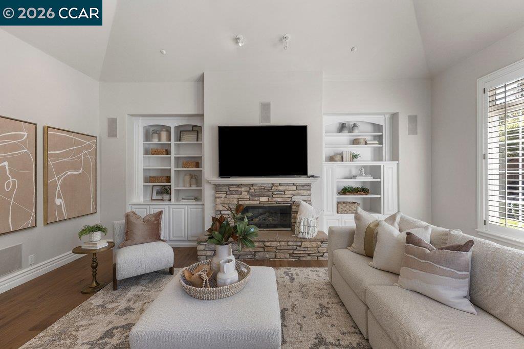 Living room with a stone fireplace, built-in shelves, and vaulted ceiling.