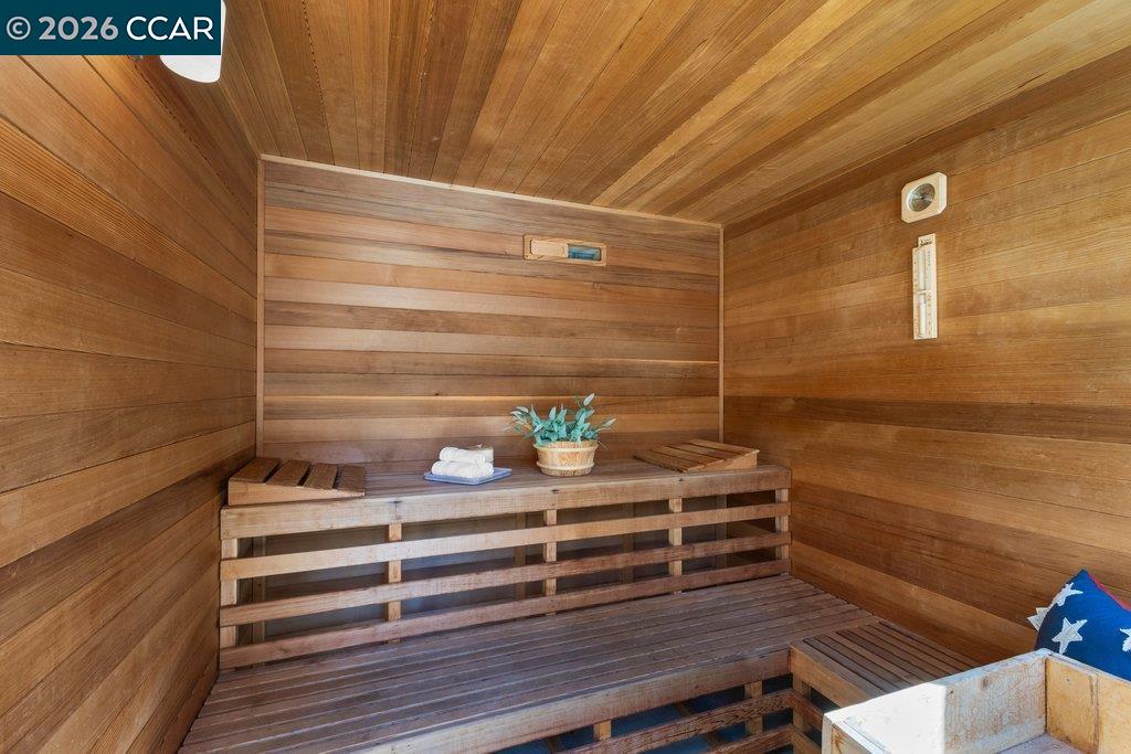 Wood-paneled sauna with tiered benches, folded towels, and a small potted plant.