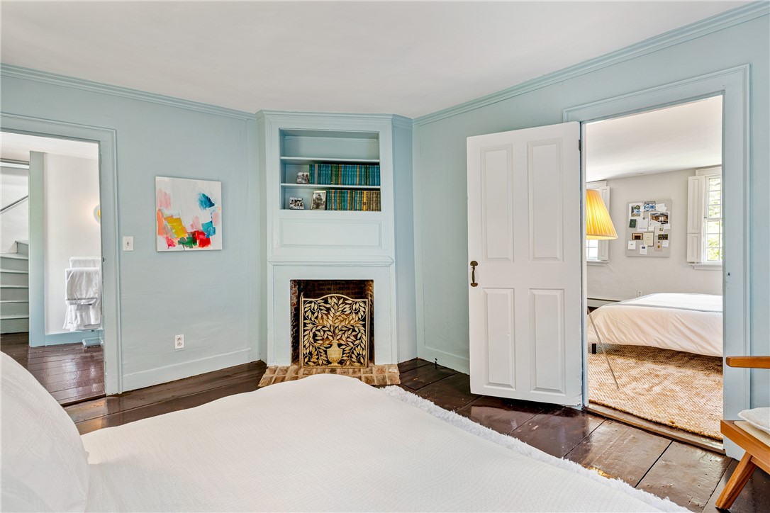 Bedroom with a white bed, built-in bookcase, and decorative fireplace surround.