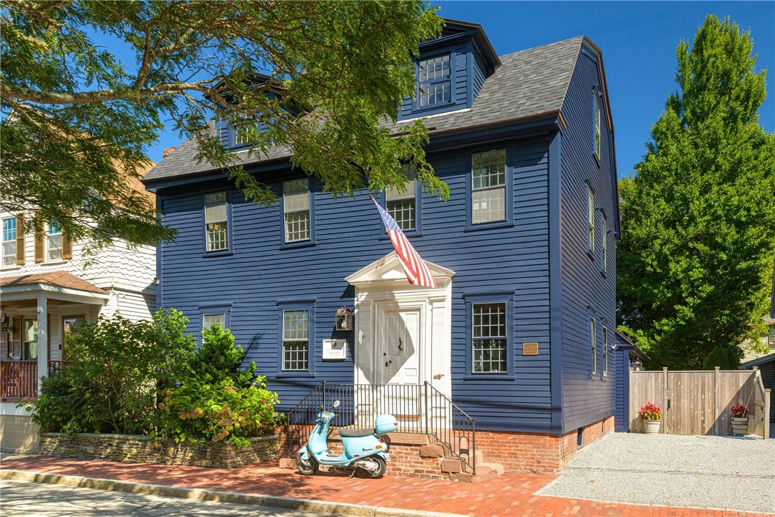 Blue-sided house with a white entry, American flag, and turquoise scooter.