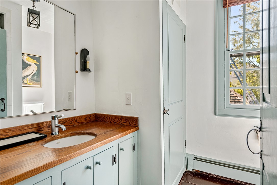 Bathroom vanity with a wooden countertop, pale blue cabinetry, and a tall divided-light window.