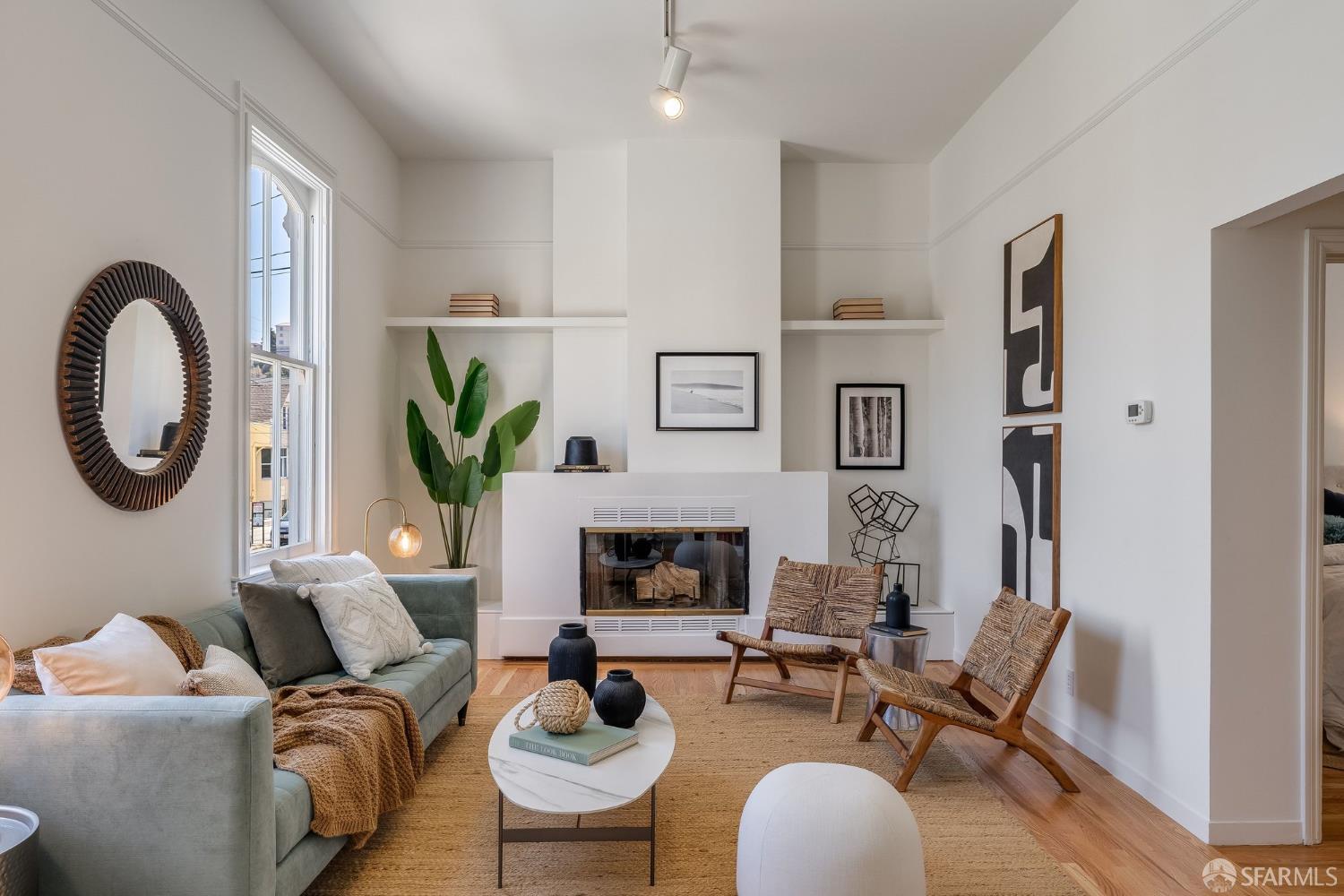 Furnished living room with a central fireplace, tall ceilings, and a large window.