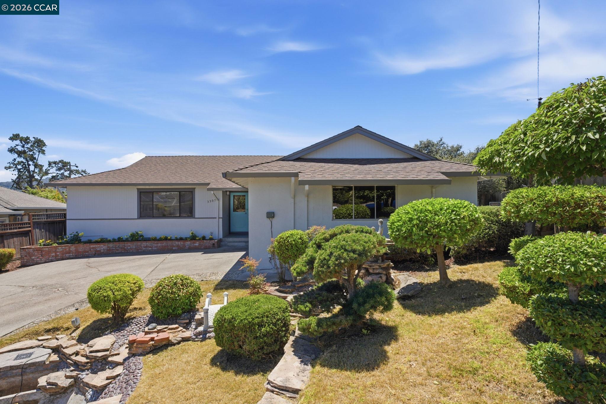 Single-story home with a blue front door, paved driveway, and landscaped front yard.