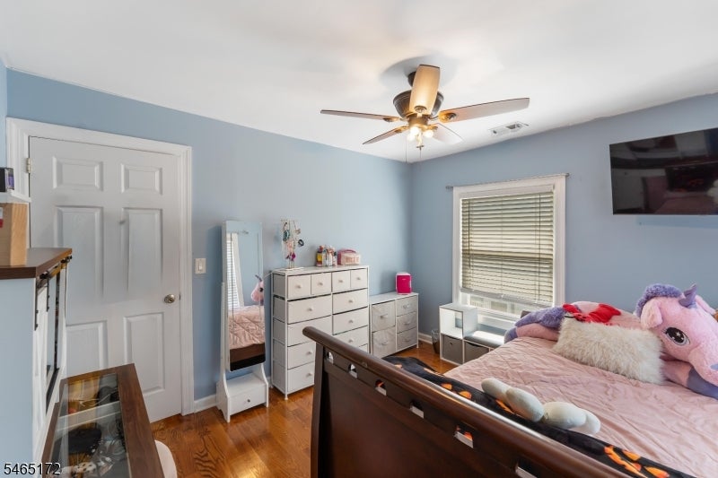 Bedroom with pale blue walls, hardwood floors, and a dark wood bed with plush toys.