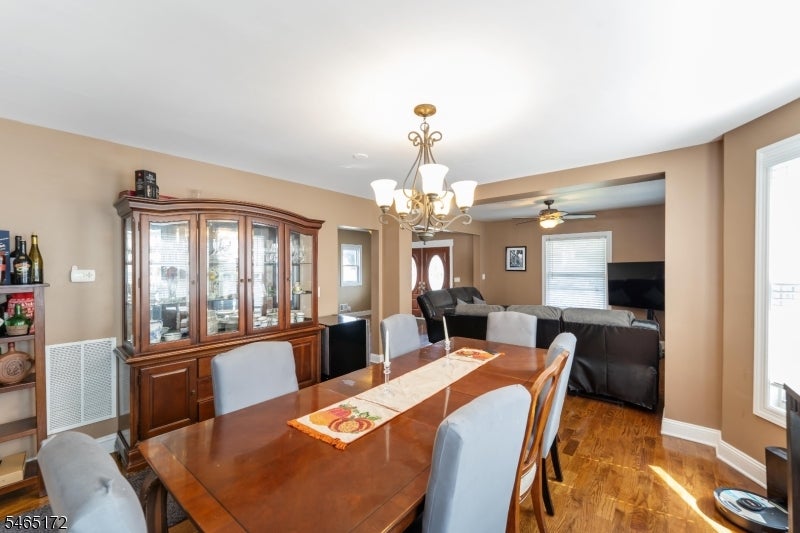 Dining room with a wooden table, glass-front china cabinet, and chandelier, opening into a living area.