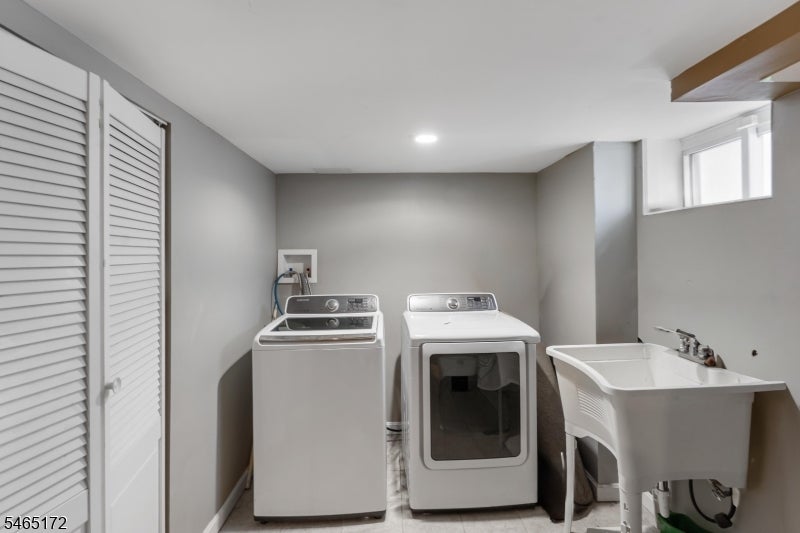 Laundry room with washer, dryer, utility sink, and louvered closet doors.