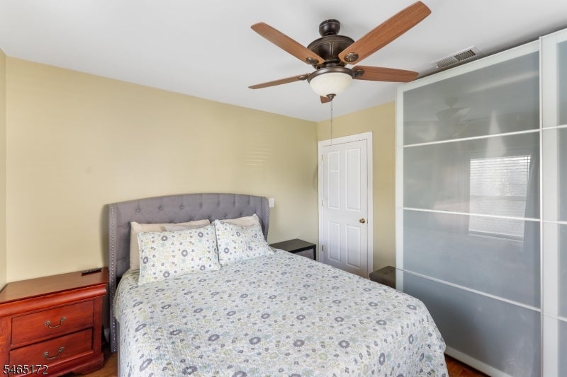 Bedroom with patterned bedding, a gray tufted headboard, and a large sliding closet door.