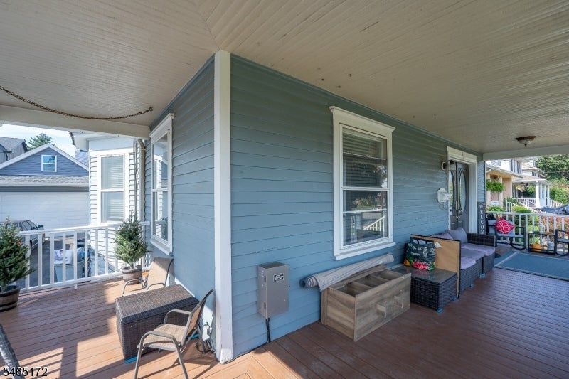 Covered porch with blue siding, wood decking, and wicker seating.