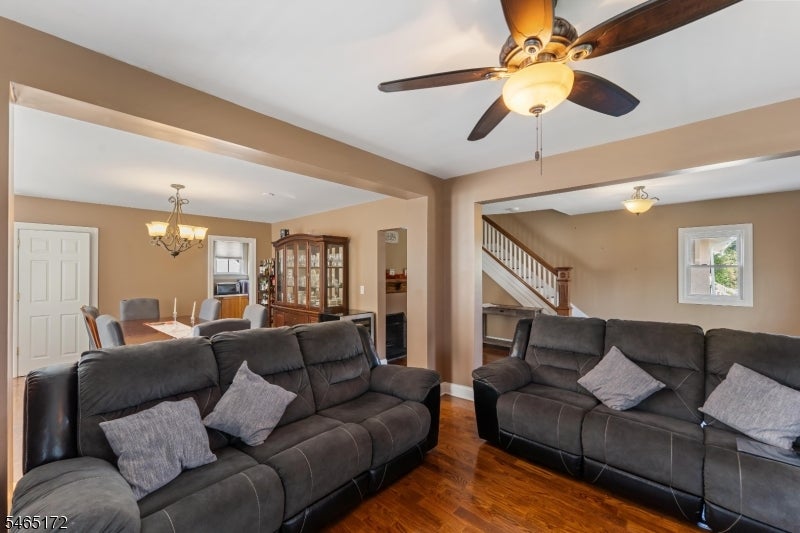 Living room with gray reclining sofas, hardwood floors, ceiling fan, and an adjoining dining area.