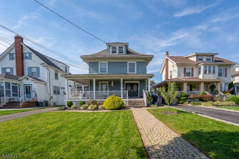 Blue two-story house with a white porch, landscaped lawn, and stone walkway.