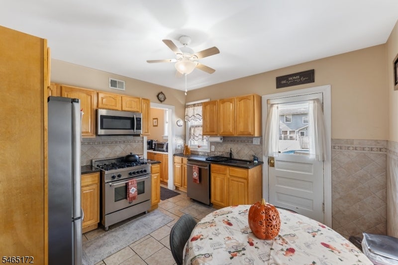 Kitchen with honey-colored cabinets, stainless steel appliances, and a floral-covered dining table.