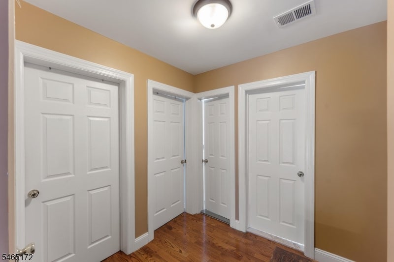 Hallway with hardwood floors and several white paneled doors.