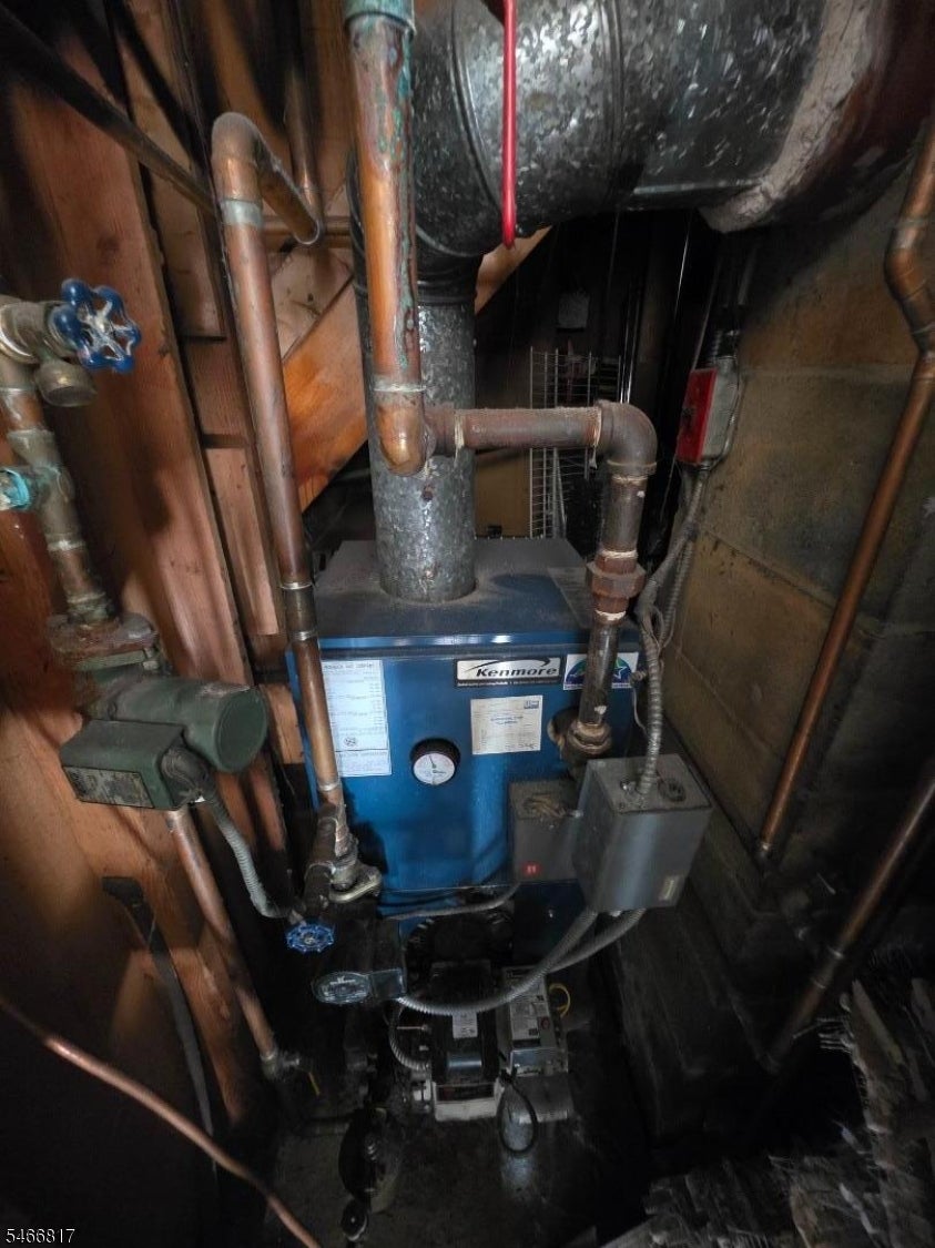 Basement boiler with exposed copper pipes and a Kenmore label.