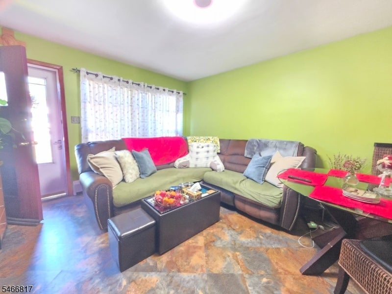 Living room with a large sectional sofa, bright green walls, and a patterned tile floor.