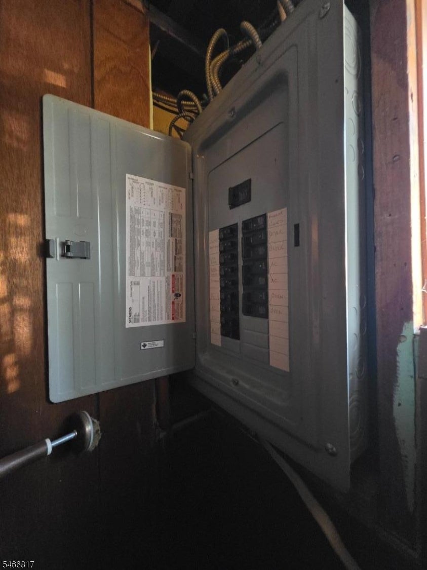 Open electrical breaker panel mounted on an unfinished wood wall.