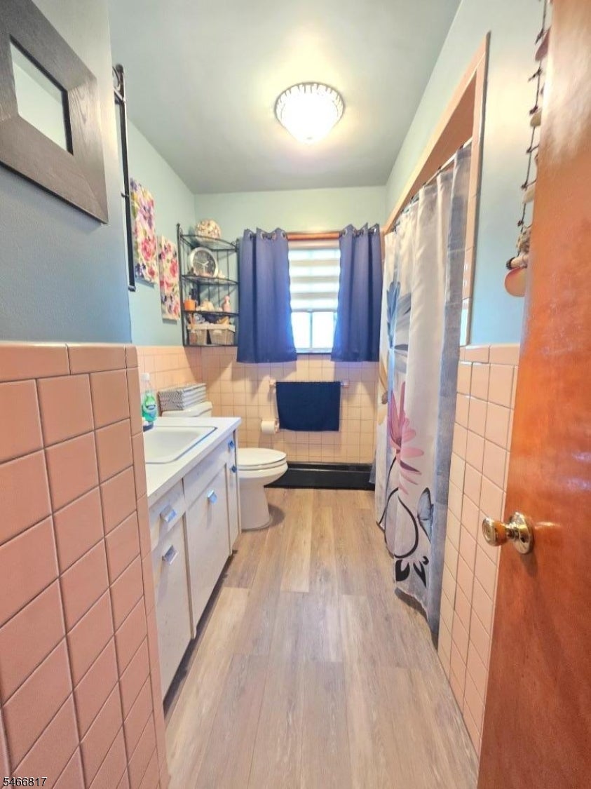 Bathroom with pink tile, a white vanity, and a patterned shower curtain.