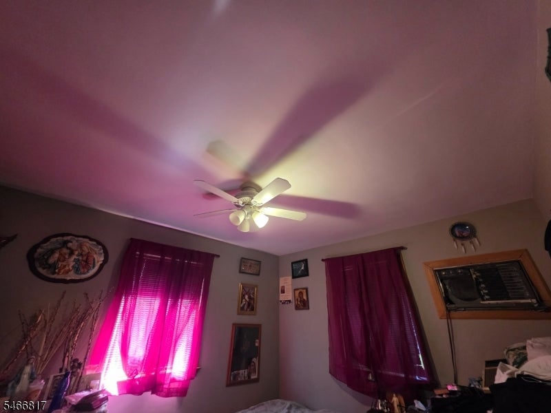 Bedroom with magenta curtains, a ceiling fan, and a window air conditioner.