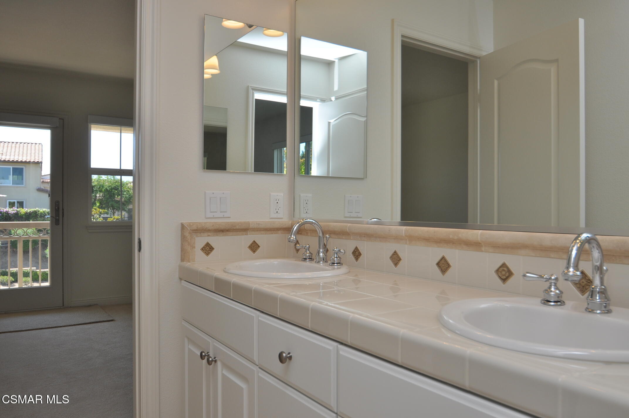 Bathroom with a double-sink tiled vanity, chrome faucets, and large mirrors.