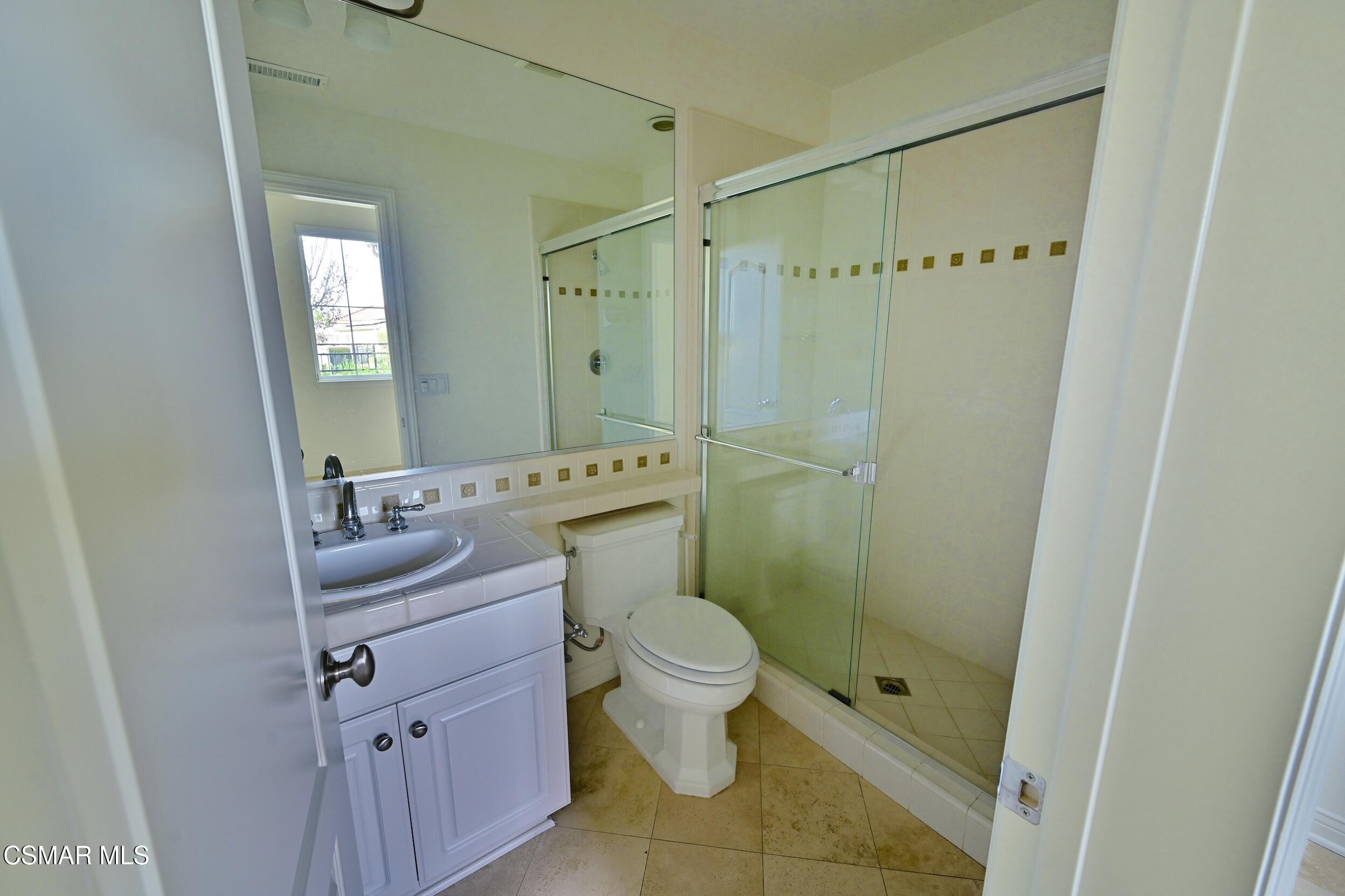 Bathroom with a white vanity and a glass-enclosed tiled shower.