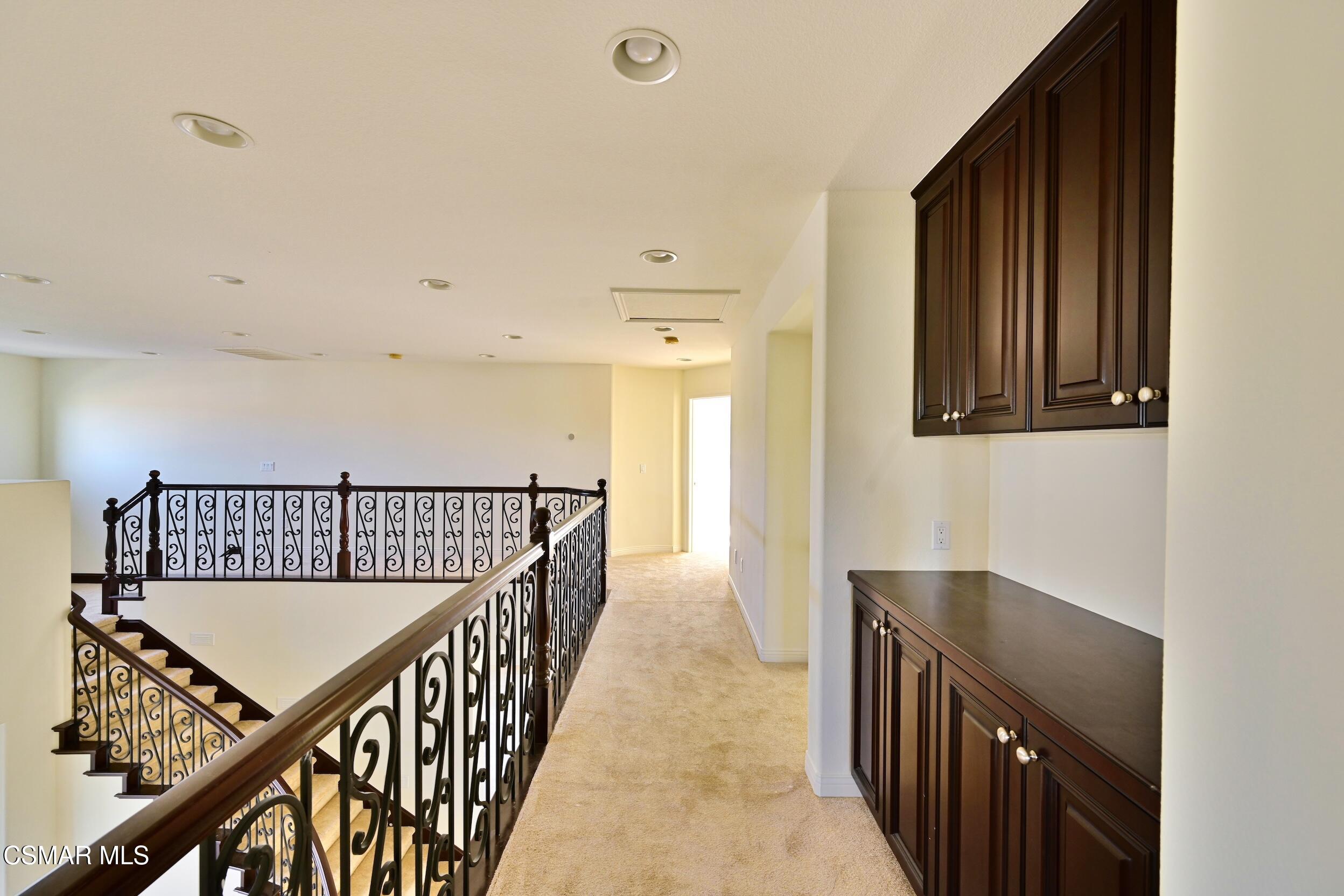 Upstairs landing with ornate stair railing and dark wood built-in cabinets.