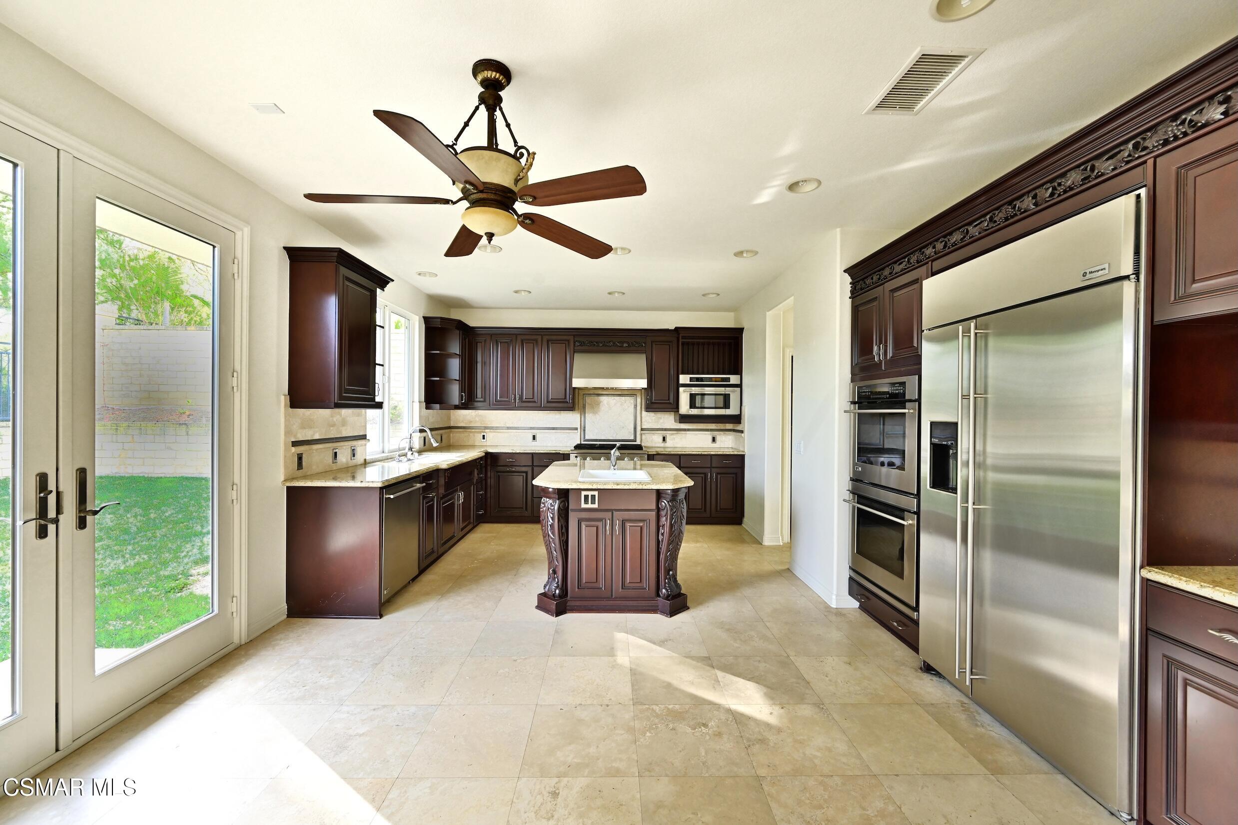 Kitchen with a carved dark wood island, stainless steel appliances, and glass doors to the yard.